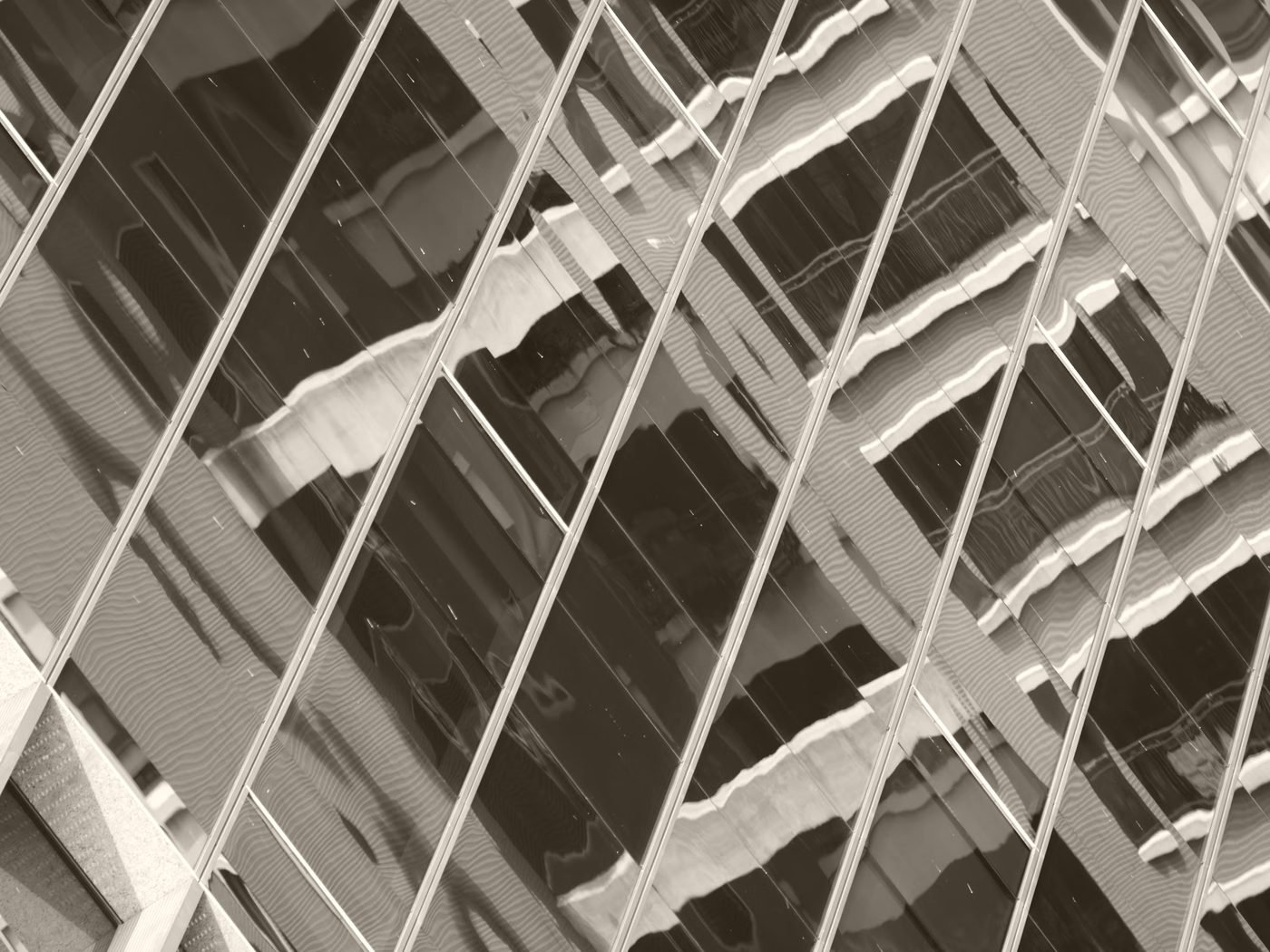 A glass curtain wall returning the street as wavering, distorted reflections
